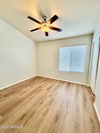 an empty room with wooden floor fan and windows