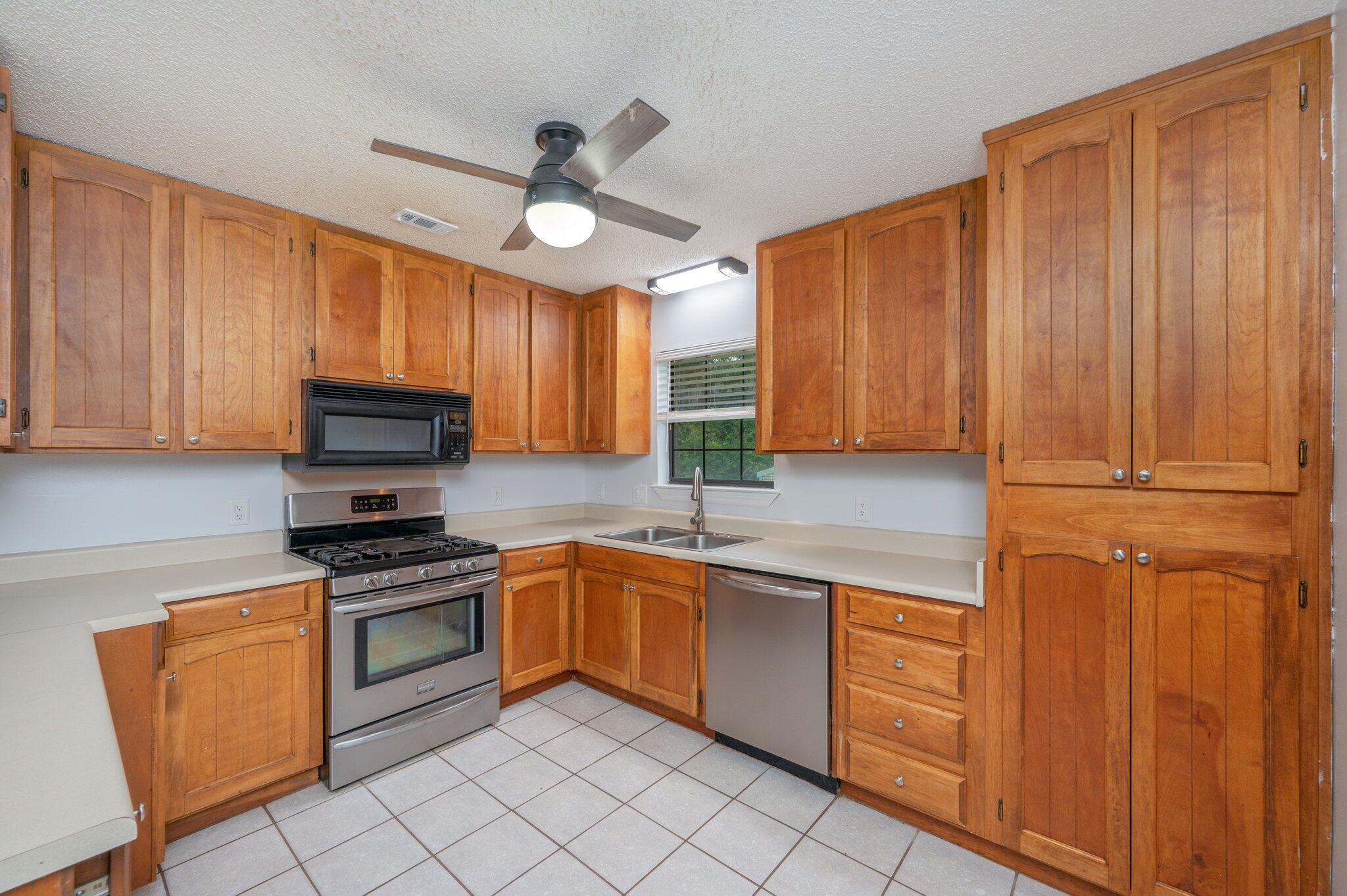 5903 Jack Stokes Road Baker, FL 32531 - Photo 11 of 35 a kitchen with stainless steel appliances granite countertop wooden cabinets a sink a stove a dining table and chairs with wooden floor
