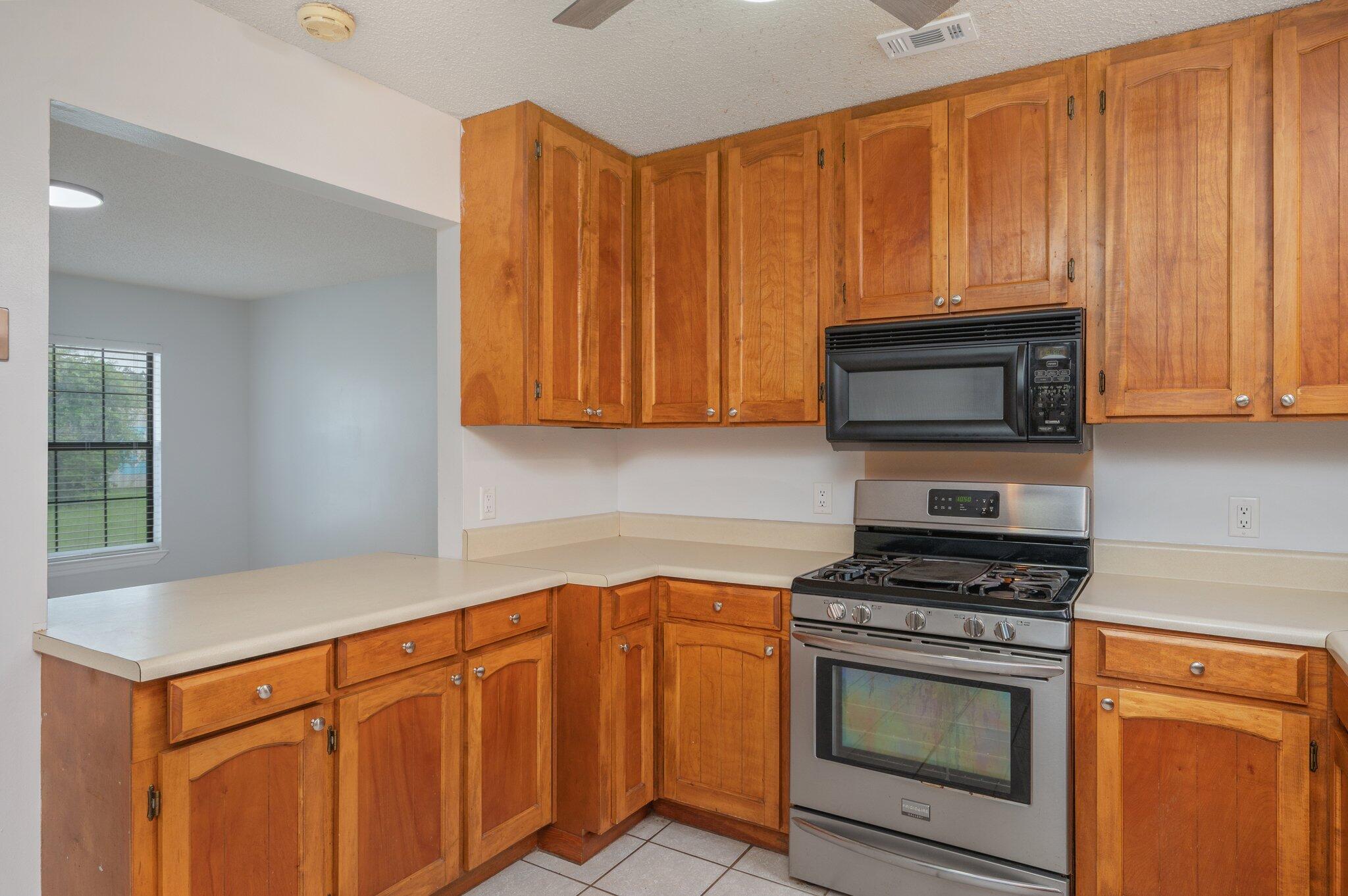 5903 Jack Stokes Road Baker, FL 32531 - Photo 13 of 35 a kitchen with stainless steel appliances granite countertop a stove microwave and cabinets