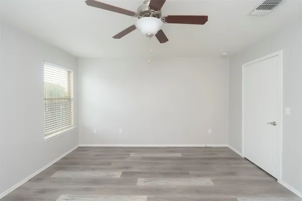 an empty room with windows and fan