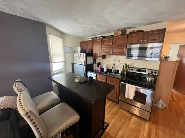 a kitchen with stainless steel appliances granite countertop a stove a sink dishwasher a dining table and chair with wooden floors