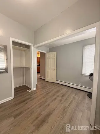 an empty room with wooden floor & closet and windows