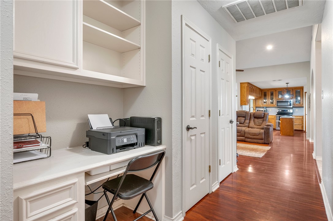 1152 McNutt Road Franklin, TX 77856 - Photo 17 of 38 a hallway with a computer on a desk and wooden floor