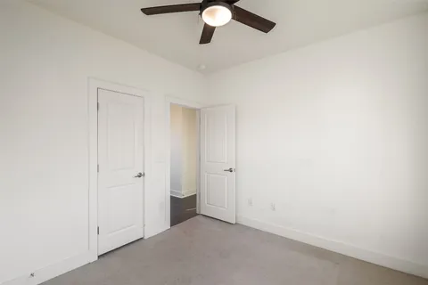 an empty room with a ceiling fan and window