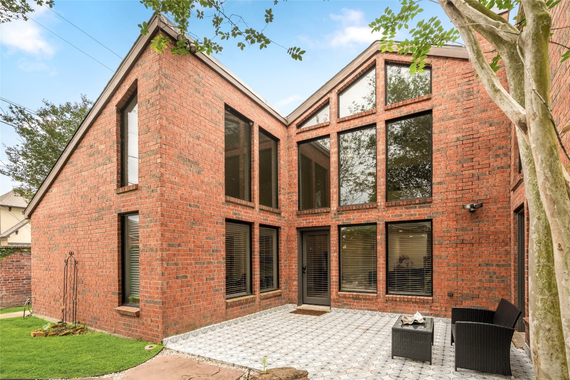 7409 South Rice Avenue Bellaire, TX 77401 - Photo 26 of 26 All-brick rear exterior with wraparound windows and a private tiled patio — an entertainer's backdrop.