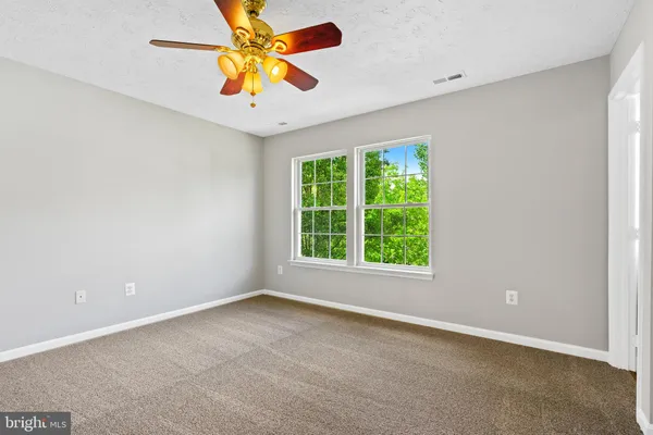 an empty room with a window and a fan
