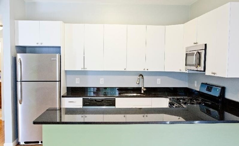 a kitchen with stainless steel appliances granite countertop a refrigerator a stove a sink a microwave and white cabinets