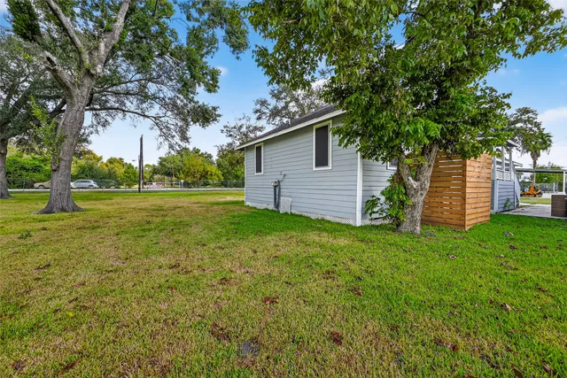 a backyard of a house with plants and large tree