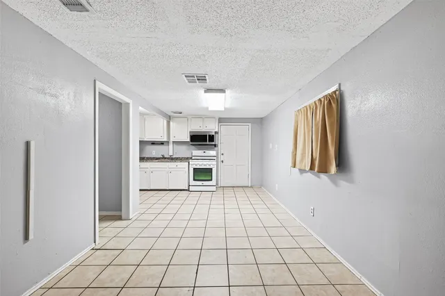a large white kitchen with a stove a sink dishwasher and cabinets