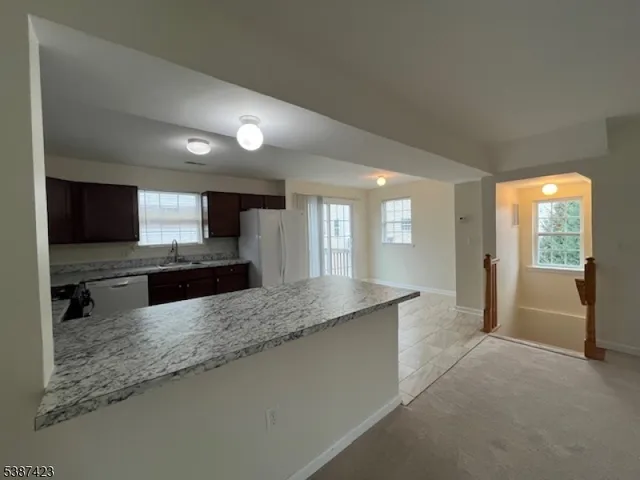 a large kitchen with kitchen island granite countertop a large counter top stainless steel appliances a sink and cabinets