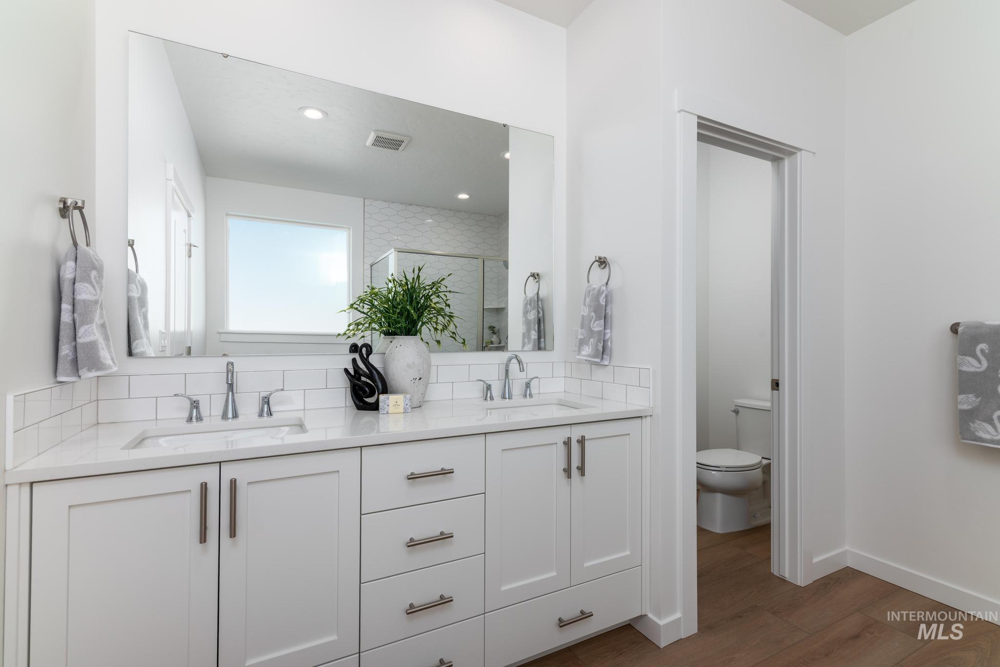 14566 Boatwatch Drive Caldwell, ID 83607 - Photo 20 of 42 Bathroom featuring double vanity, a shower stall, dark wood-style floors, and decorative backsplash