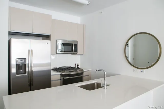a kitchen with stainless steel appliances a refrigerator a sink a stove and white cabinets