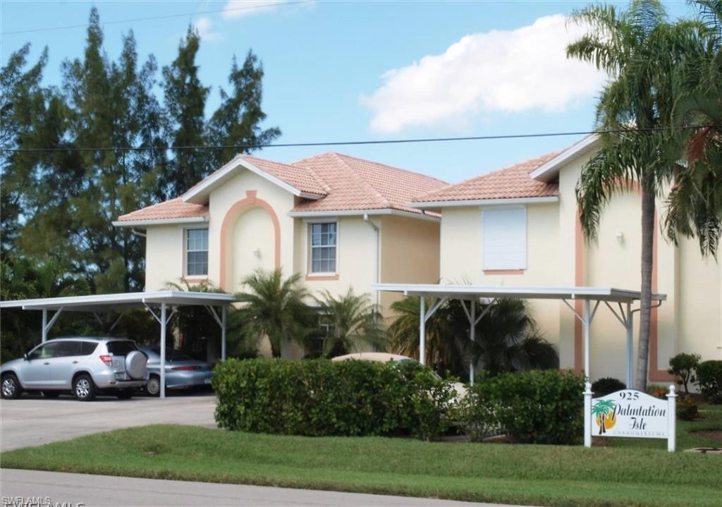 925 Southwest 47th Terrace, Unit 101 Cape Coral, FL 33914 - Photo 1 of 48 a view of a white house with large windows and a table and chairs under an umbrella