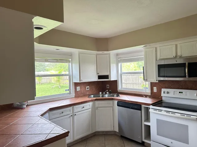 a kitchen with granite countertop a stove a sink and a microwave