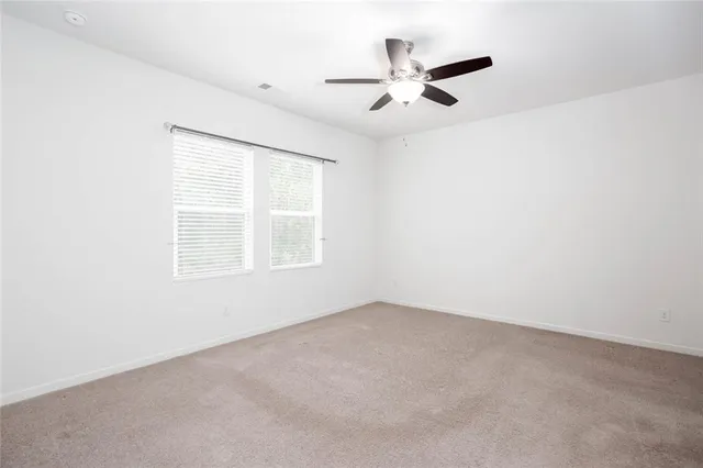 an empty room with a ceiling fan and carpet