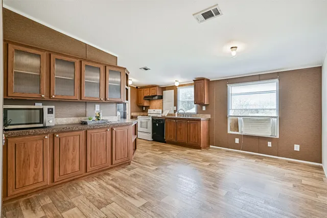 a large kitchen with stainless steel appliances granite countertop a large stove top oven a sink dishwasher and white cabinets with wooden floor