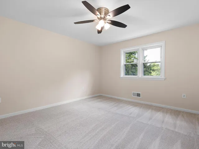 an empty room with a window and a fan