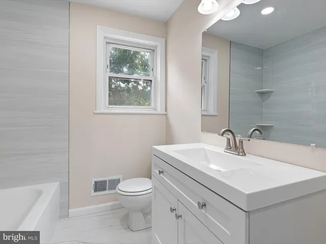 a bathroom with a sink toilet vanity and window