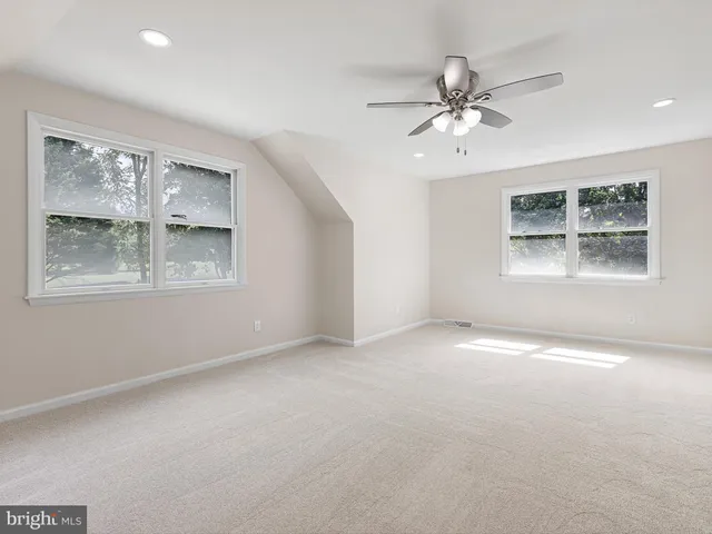 an empty room with windows and ceiling fan