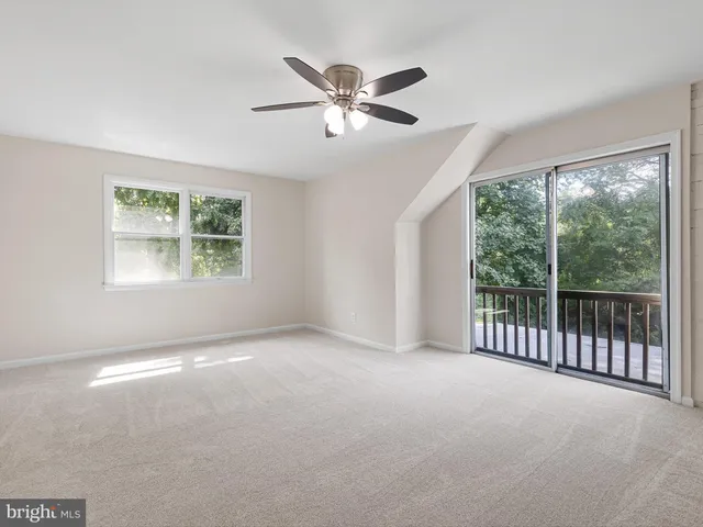 an empty room with windows and ceiling fan