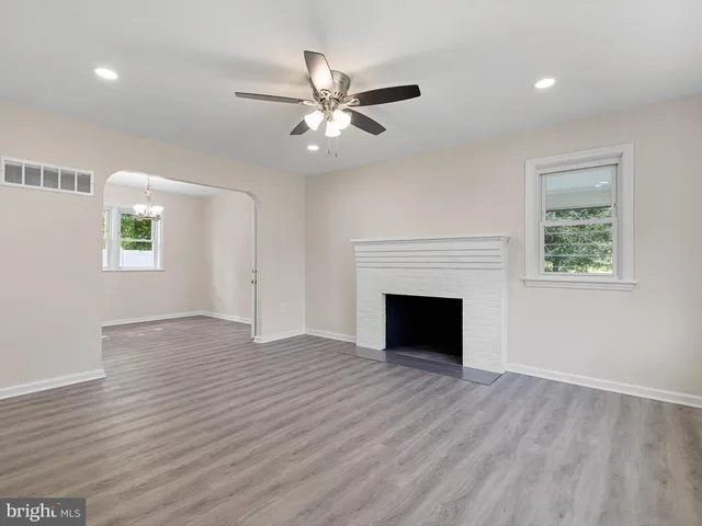 a view of an empty room with wooden floor and a fireplace