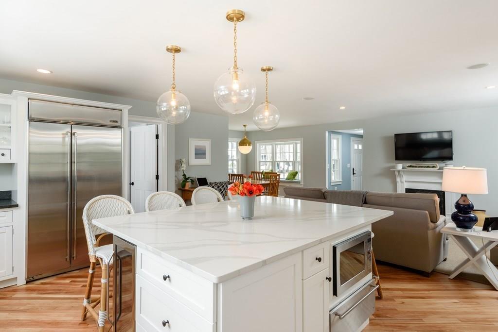 a large kitchen with granite countertop a stove a sink a refrigerator and a dining table with wooden floor