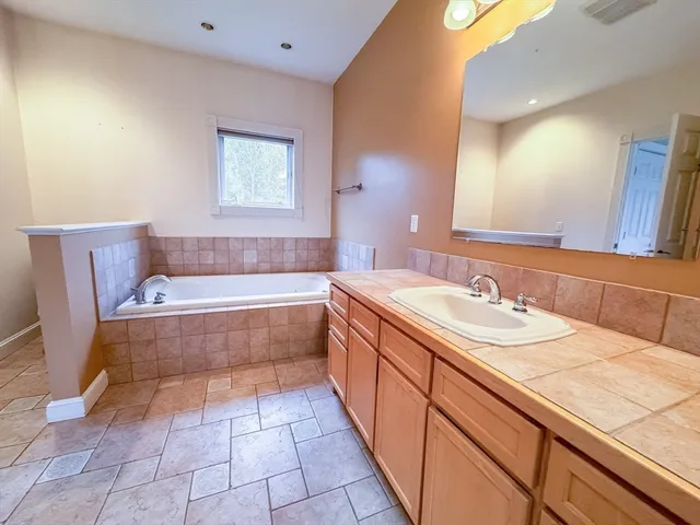 a spacious bathroom with a bathtub sink and mirror