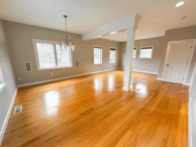 a view of an empty room with window and wooden floor