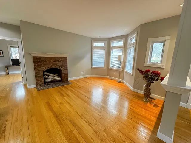 a view of empty room with wooden floor and fireplace