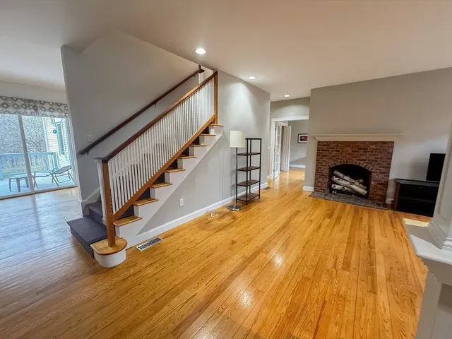 a view of an empty room with wooden floor and fireplace