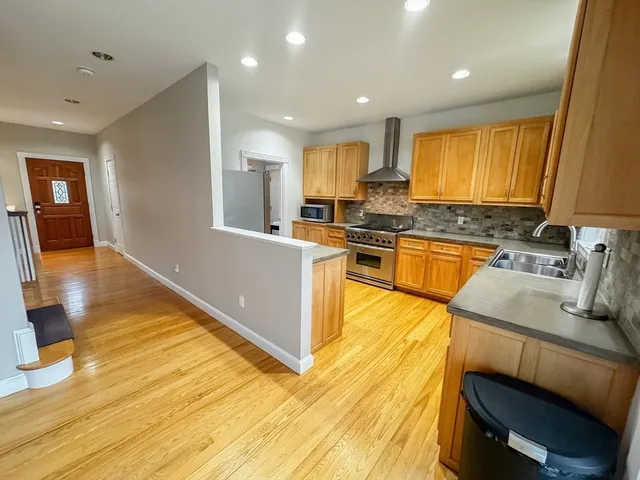 a large kitchen with stainless steel appliances granite countertop a stove a sink dishwasher and a microwave oven with wooden floor