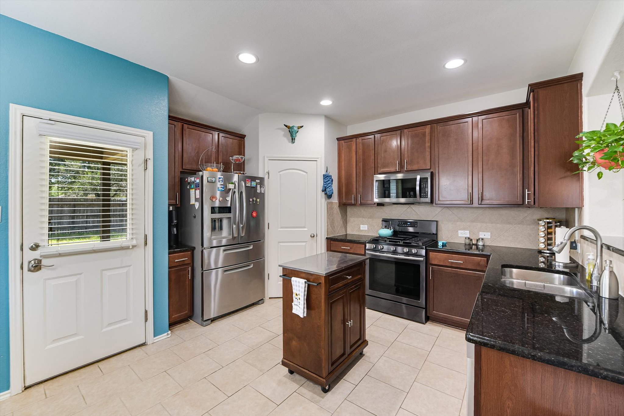 536 Dragon Ridge Road Buda, TX 78610 - Photo 7 of 20 Kitchen featuring dark wood cabinetry, stainless steel appliances, granite countertops, and tile flooring