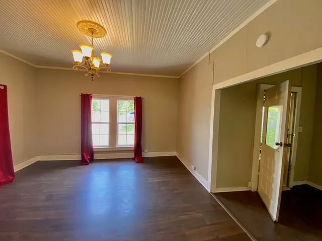 a view of an empty room with glass door and wooden floor
