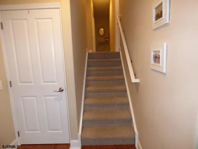 a view of staircase with white walls and white door