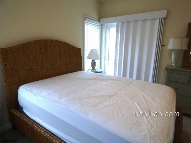 a large white bed in a bedroom next to a window