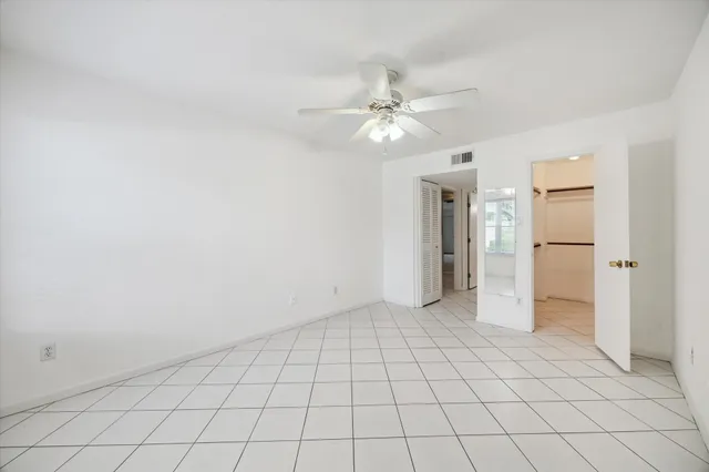 an empty room with windows and fan