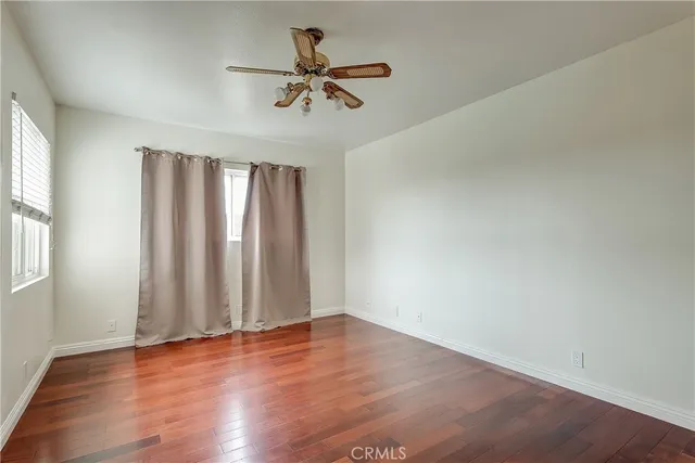 an empty room with wooden floor fan and windows