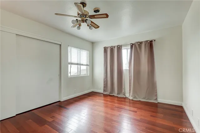 an empty room with wooden floor chandelier fan and windows