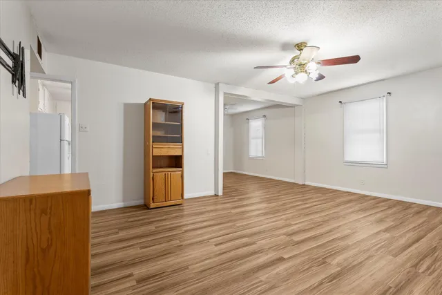 a view of an empty room with a window and wooden floor