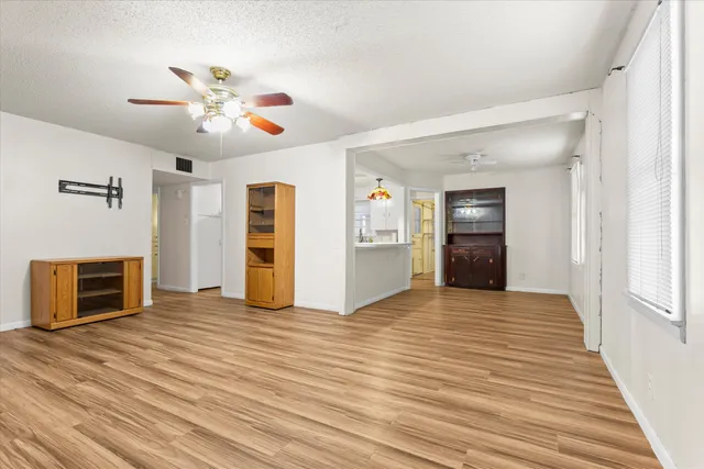 a view of an empty room with wooden floor fireplace and a window