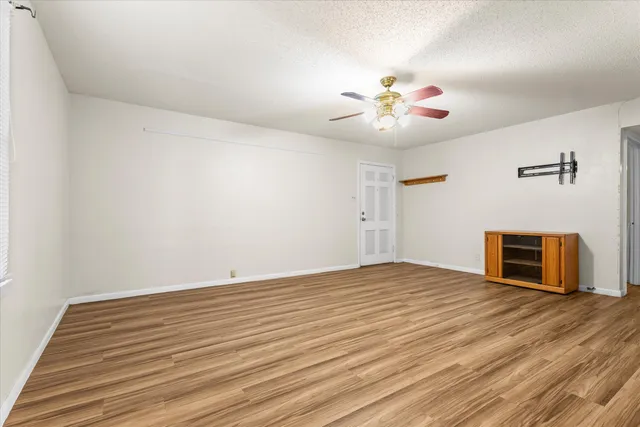 a view of an empty room with a ceiling fan and a window