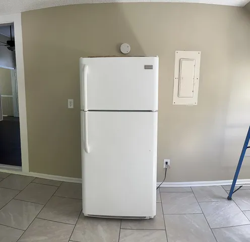 a view of kitchen with refrigerator and white wall