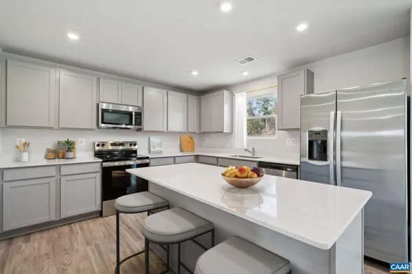 a kitchen with a sink a stove a refrigerator cabinets and a dining table