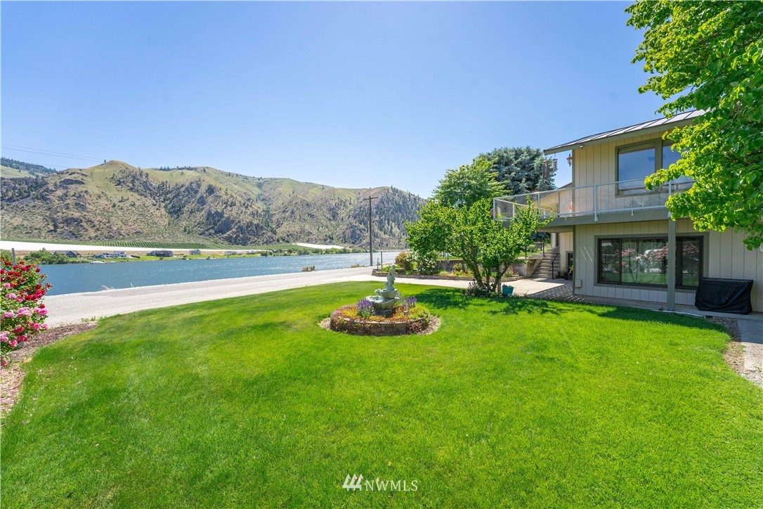 485 Stayman Flats Road Chelan, WA 98816 - Photo 22 of 32 a view of a garden with lawn chairs under an umbrella