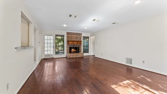 an empty room with wooden floor fireplace and windows
