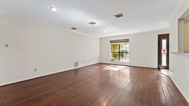 an empty room with wooden floor fireplace and windows