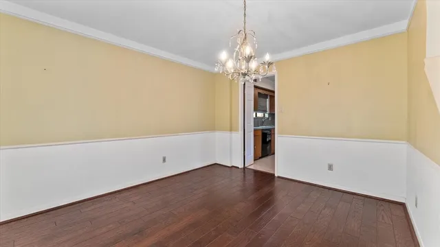 a view of empty room with wooden floor and chandelier