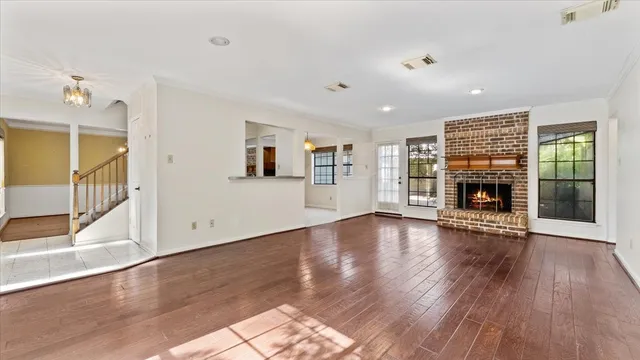 an empty room with wooden floor fireplace and windows