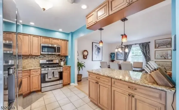 a kitchen with stainless steel appliances granite countertop a stove top oven a sink dishwasher and a refrigerator