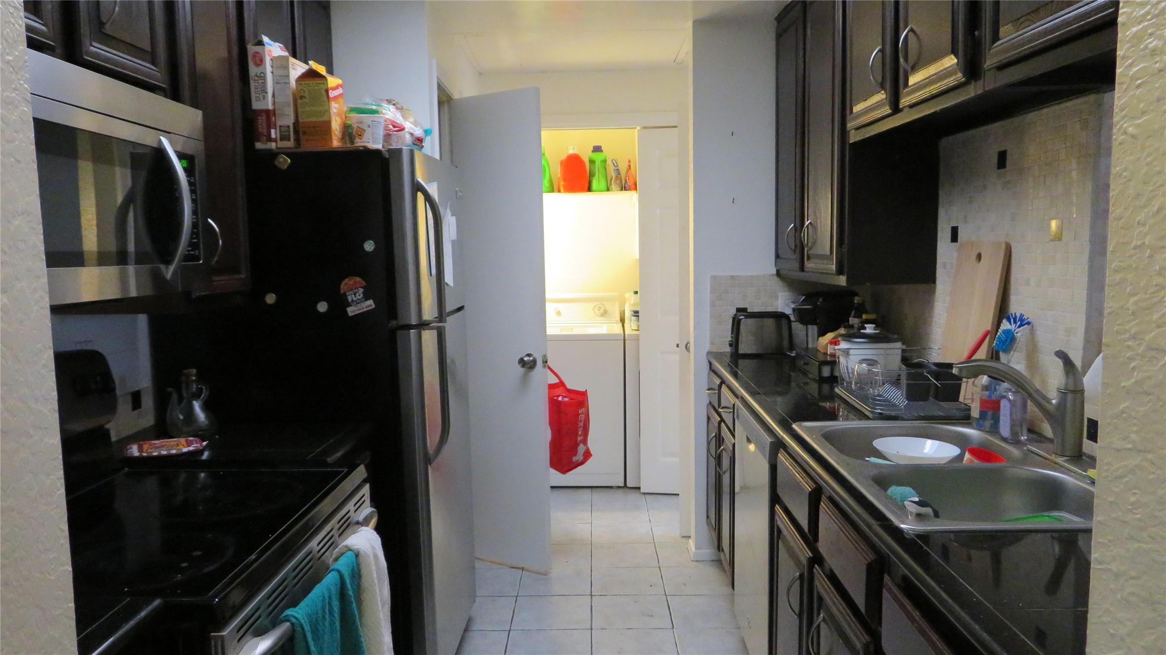 806 West 24th Street, Unit 200 Austin, TX 78705 - Photo 14 of 33 A compact kitchen with sleek appliances and dark cabinetry offers practical functionality, featuring a dedicated laundry nook.